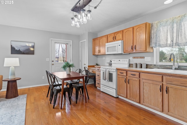 kitchen with sink, an inviting chandelier, hanging light fixtures, white appliances, and light hardwood / wood-style floors