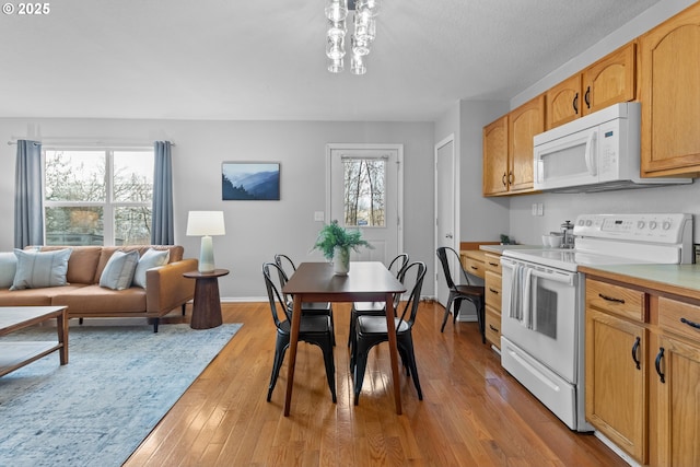 kitchen with light wood-type flooring, a chandelier, and white appliances