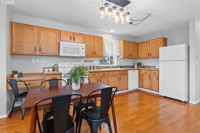 kitchen featuring pendant lighting, white appliances, sink, and light hardwood / wood-style flooring