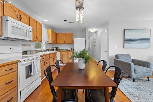 kitchen featuring white appliances, sink, and light wood-type flooring