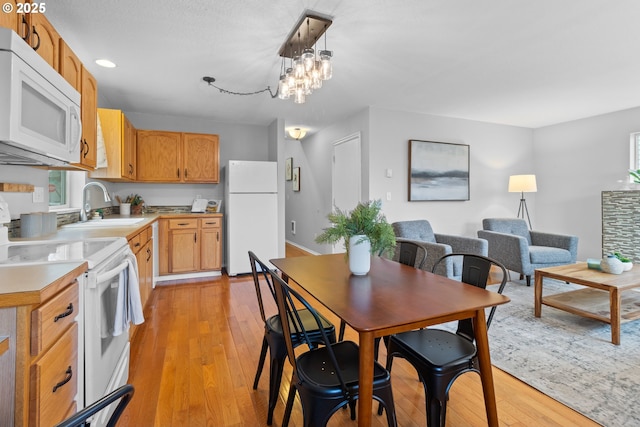 dining room featuring sink, a chandelier, and light wood-type flooring