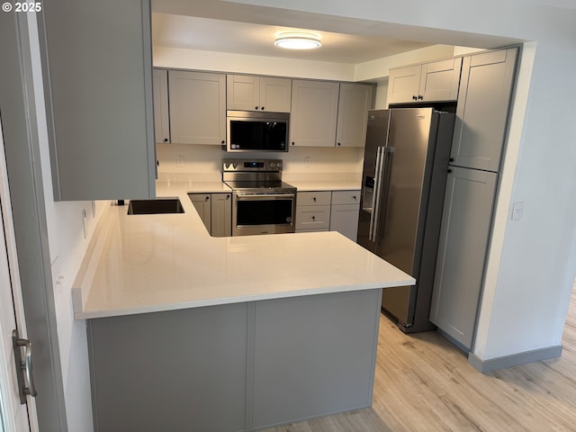 2420 Margery St, West Linn, OR 97068 - kitchen with stainless steel appliances, gray cabinets, light wood finished floors, and a peninsula