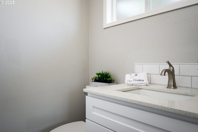 half bath with a textured wall and vanity