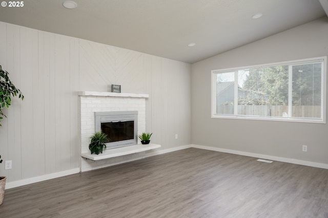 unfurnished living room featuring lofted ceiling, recessed lighting, a fireplace, wood finished floors, and baseboards