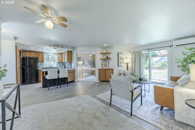 397 S 32nd St, Springfield, OR 97478 - living area featuring ceiling fan, light wood-type flooring, a wall mounted air conditioner, and a textured ceiling