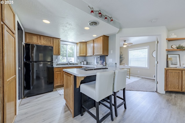 397 S 32nd St, Springfield, OR 97478 - kitchen with freestanding refrigerator, light wood-style floors, a kitchen breakfast bar, light countertops, and a peninsula