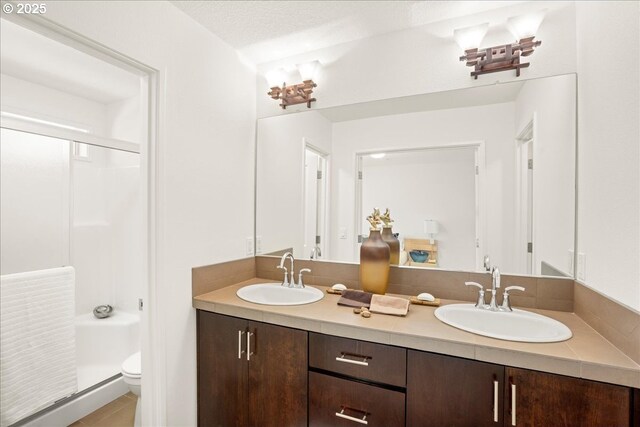 4891 NW Blandy Ter, Portland, OR 97229 - full bathroom with an enclosed shower, toilet, double vanity, and tile patterned flooring