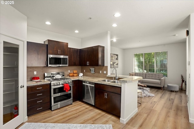 4891 NW Blandy Ter, Portland, OR 97229 - kitchen featuring stainless steel appliances, a sink, a peninsula, light countertops, and recessed lighting