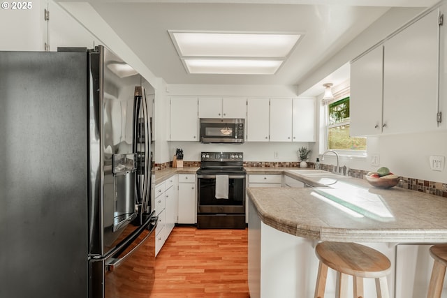 kitchen featuring black fridge, kitchen peninsula, sink, and range with electric stovetop