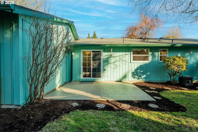 view of exterior entry featuring central AC unit and a patio