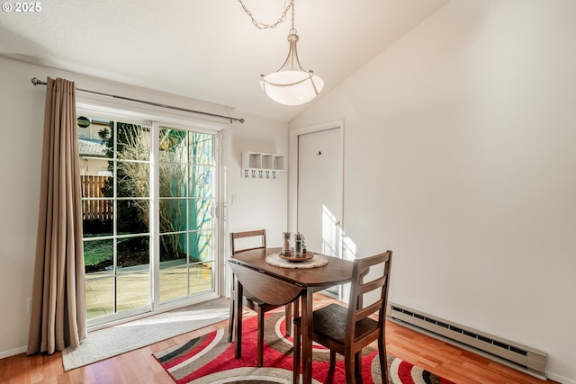 dining area with vaulted ceiling, light wood-type flooring, and a baseboard heating unit