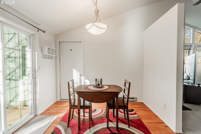 dining room featuring vaulted ceiling, light wood-type flooring, and a baseboard radiator