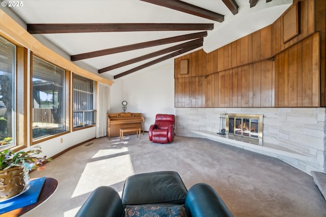 living room with visible vents, lofted ceiling with beams, a glass covered fireplace, light carpet, and baseboards