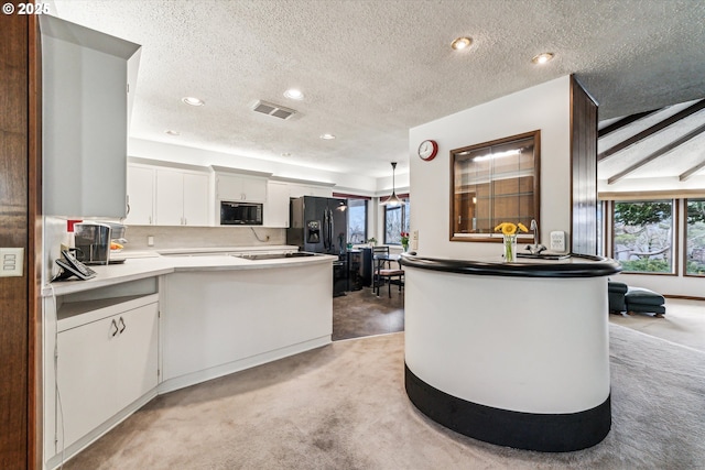 kitchen with visible vents, white cabinets, light carpet, and black appliances