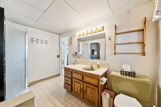 full bath featuring toilet, vanity, a drop ceiling, baseboards, and tile patterned floors