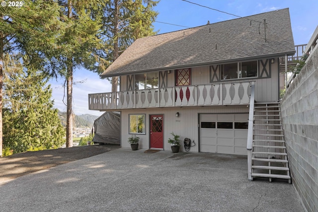 view of front of home featuring stairway, an attached garage, a shingled roof, and aphalt driveway