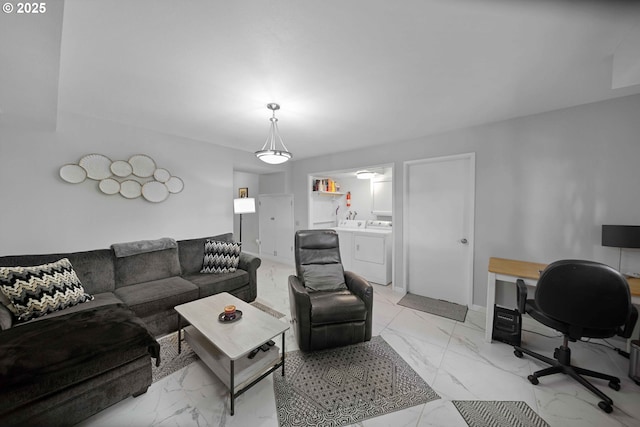 living area featuring marble finish floor, baseboards, and independent washer and dryer