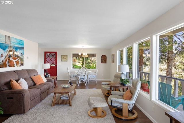 living room with an inviting chandelier, a healthy amount of sunlight, wood finished floors, and baseboards