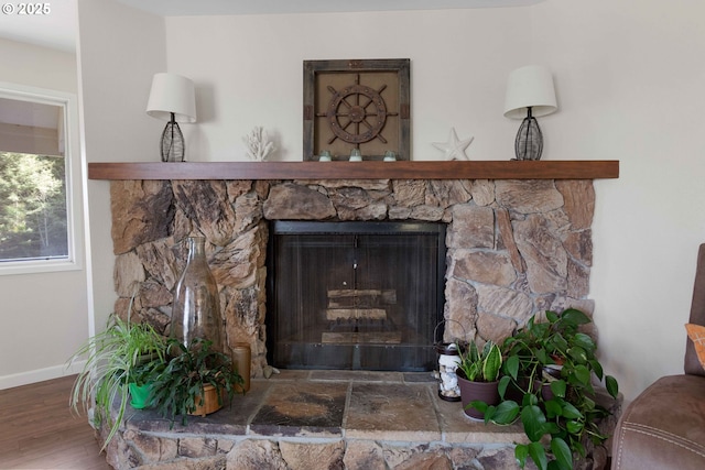 interior details with baseboards, wood finished floors, and a stone fireplace