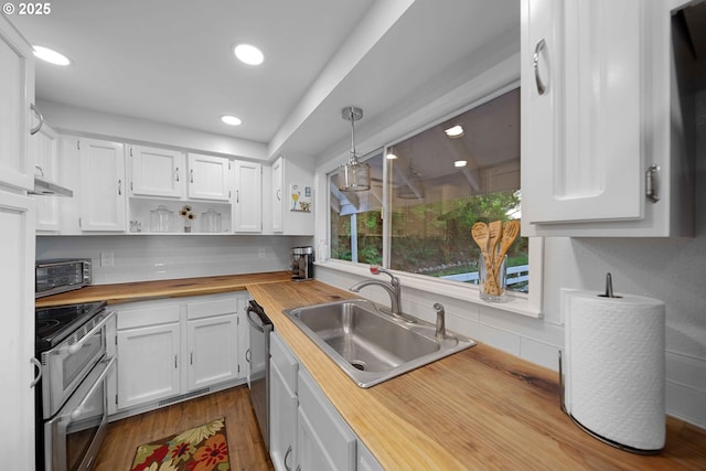 kitchen with butcher block countertops, a sink, white cabinetry, appliances with stainless steel finishes, and dark wood-type flooring