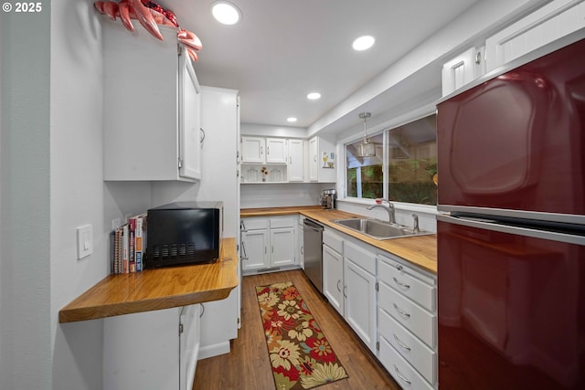 kitchen with butcher block counters, stainless steel dishwasher, freestanding refrigerator, and a sink