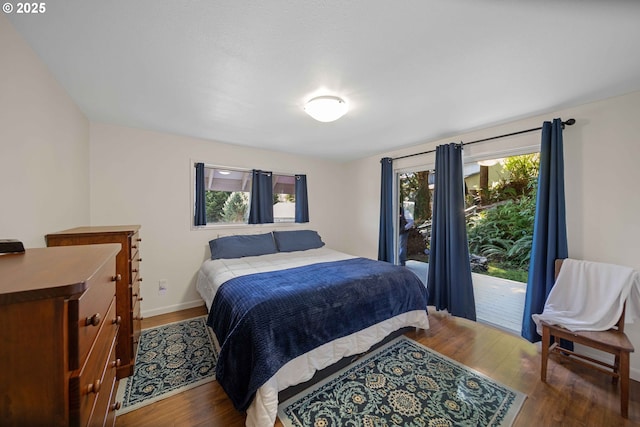 bedroom with wood finished floors, baseboards, and access to outside