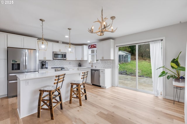 110 Axis Rd, Castle Rock, WA 98611 - kitchen with stainless steel appliances, a sink, a breakfast bar area, decorative backsplash, and light wood-style floors