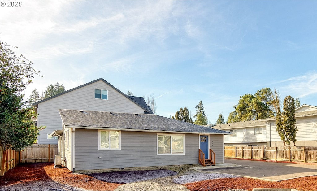 view of front of property with entry steps, a shingled roof, and a fenced backyard