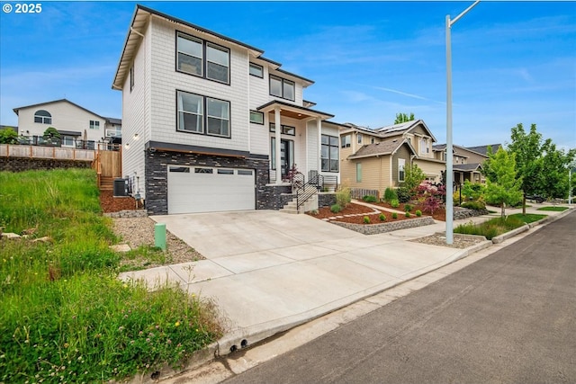 view of front of property featuring a garage, stone siding, driveway, fence, and central AC