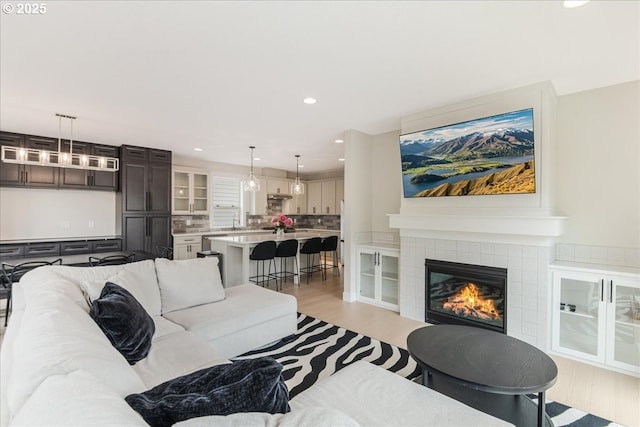 living room featuring recessed lighting, light wood-style flooring, and a tiled fireplace