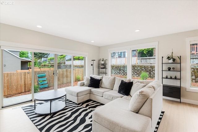living room featuring healthy amount of natural light, recessed lighting, light wood-type flooring, and baseboards