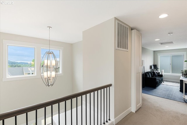 hallway featuring light colored carpet, a chandelier, recessed lighting, baseboards, and an upstairs landing