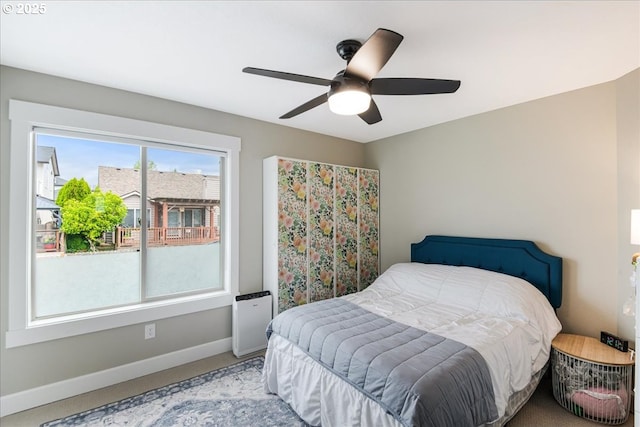 carpeted bedroom featuring baseboards and a ceiling fan