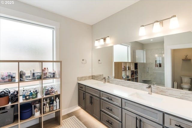 full bathroom featuring a stall shower, double vanity, toilet, tile patterned flooring, and baseboards