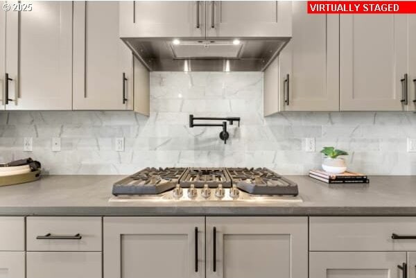 10494 SE Reverent Rd Unit 315, Happy Valley, OR 97086 - kitchen with stainless steel gas stovetop, white cabinets, under cabinet range hood, and tasteful backsplash