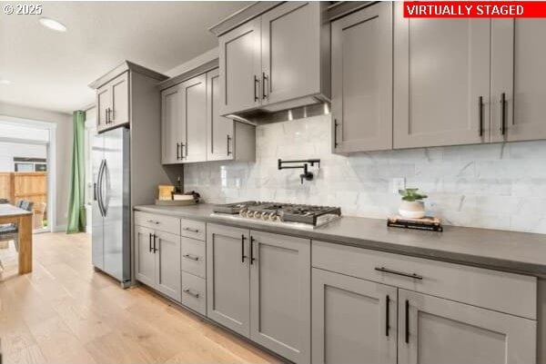 10494 SE Reverent Rd Unit 315, Happy Valley, OR 97086 - kitchen featuring gray cabinetry, decorative backsplash, light wood-style floors, and stainless steel appliances