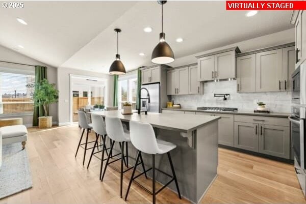 10494 SE Reverent Rd Unit 315, Happy Valley, OR 97086 - kitchen with decorative backsplash, a breakfast bar area, a center island with sink, gray cabinetry, and recessed lighting