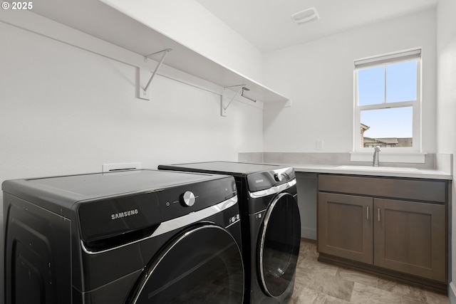 washroom with washer and dryer, sink, and cabinets