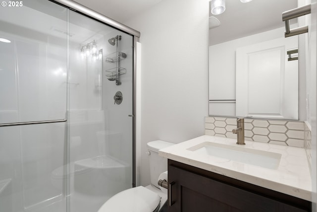 bathroom with a shower with shower door, vanity, backsplash, and toilet