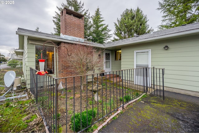 property entrance with a chimney, fence, and brick siding