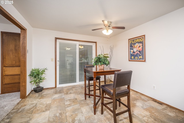 dining area with stone finish flooring, visible vents, and ceiling fan