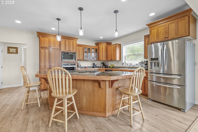 245 NE Balm St, Sheridan, OR 97378 - kitchen featuring appliances with stainless steel finishes, light wood-style flooring, brown cabinetry, recessed lighting, and glass insert cabinets
