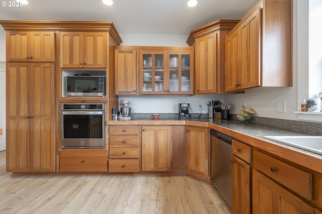 245 NE Balm St, Sheridan, OR 97378 - kitchen with appliances with stainless steel finishes, light wood-style flooring, brown cabinetry, recessed lighting, and glass insert cabinets