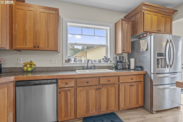 245 NE Balm St, Sheridan, OR 97378 - kitchen with appliances with stainless steel finishes, a sink, brown cabinetry, tile countertops, and light wood finished floors