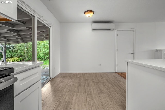 interior space featuring baseboards, a wall unit AC, and light wood-type flooring