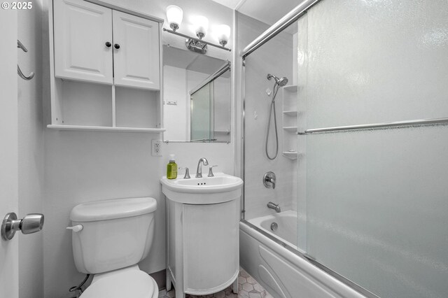 bathroom with toilet, combined bath / shower with glass door, and a sink