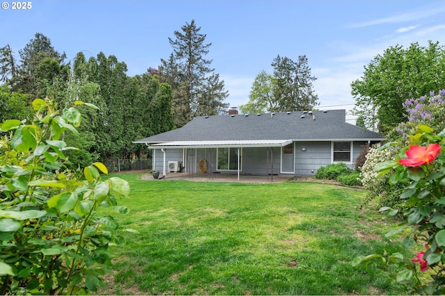 rear view of property featuring fence, a shingled roof, a lawn, and a patio area