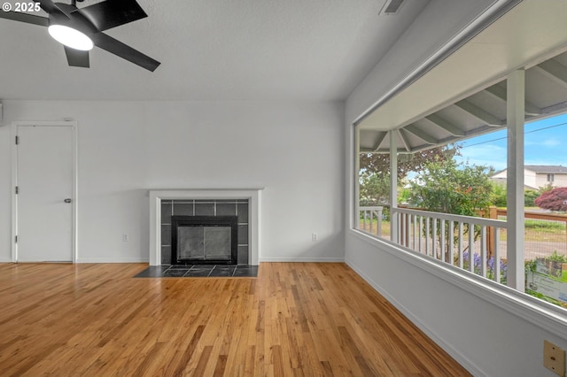 unfurnished living room with baseboards, a ceiling fan, wood finished floors, and a wealth of natural light