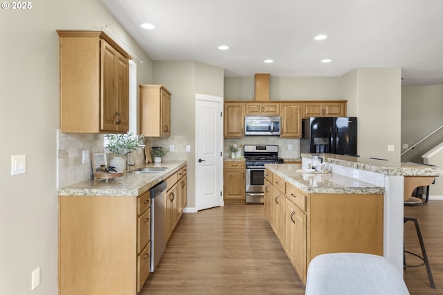 3678 Snowberry Rd, Eugene, OR 97403 - kitchen featuring appliances with stainless steel finishes, a kitchen island, a kitchen bar, light wood finished floors, and recessed lighting