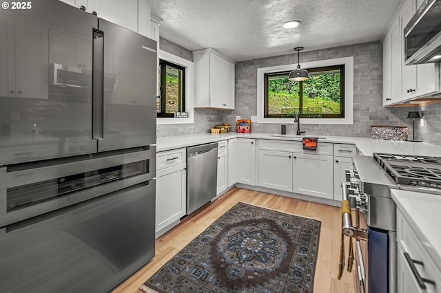19919 SE Borges Rd, Damascus, OR 97089 - kitchen featuring stainless steel appliances, a sink, a textured ceiling, backsplash, and light wood-type flooring